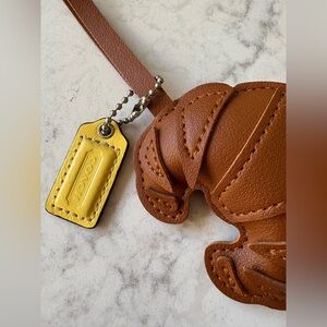 Brown Croissant Bag Charm with Yellow Coach Tag